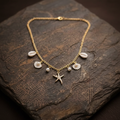 Gold Ocean Charm Necklace on stone surface studio shot